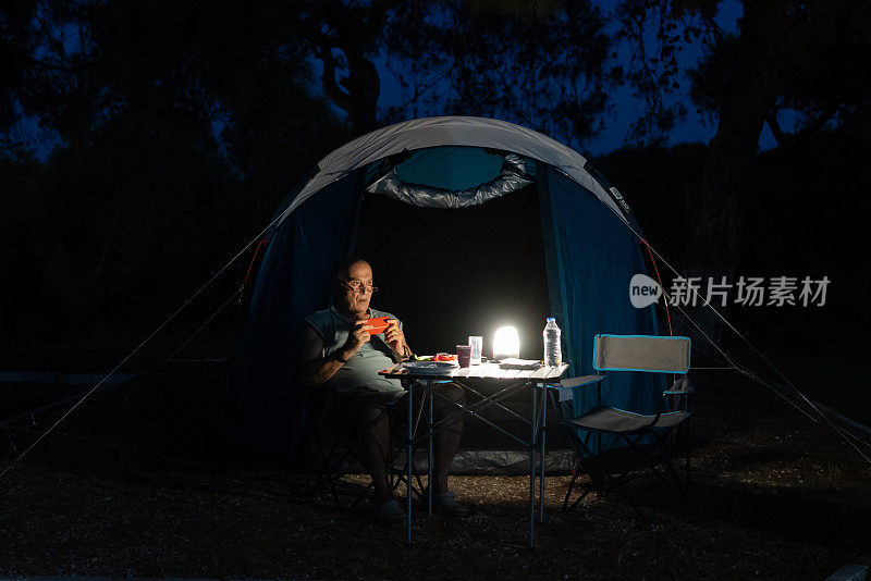 一个老人在露营的时候一边放松一边用手机