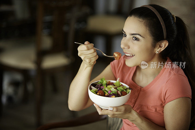 一个西班牙裔可爱的年轻女子午餐吃素食沙拉的特写镜头