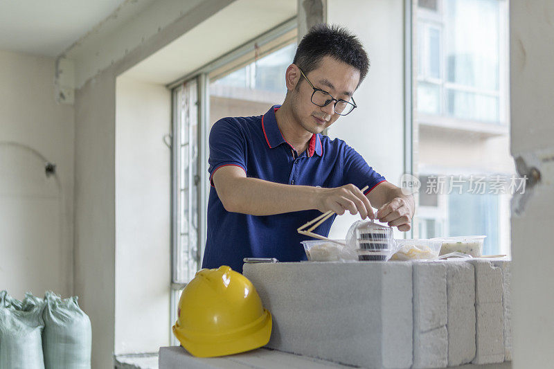 亚洲男工程师在装修工地吃外卖