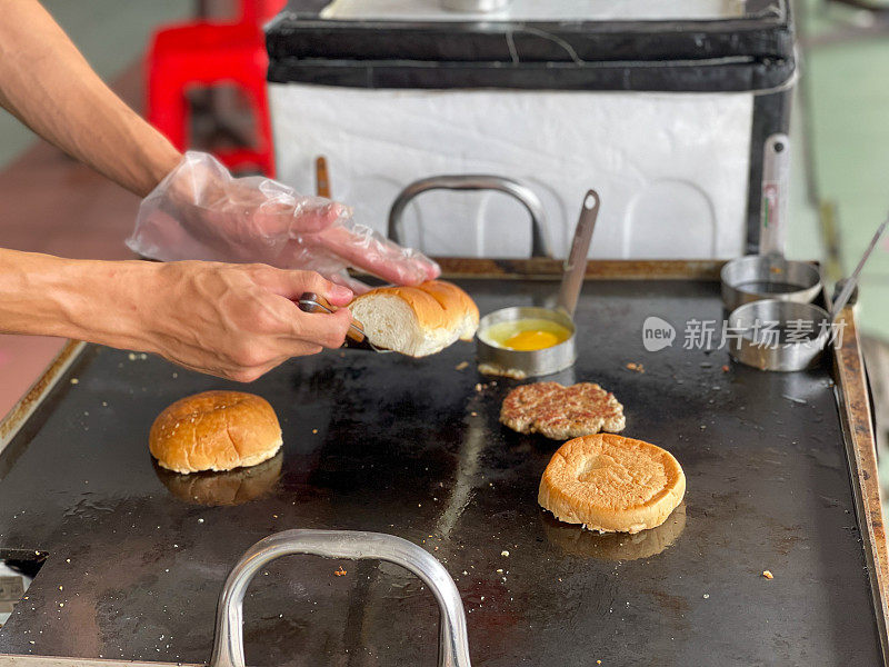 一名男子正在用手烹饪猪肉汉堡。街头食品