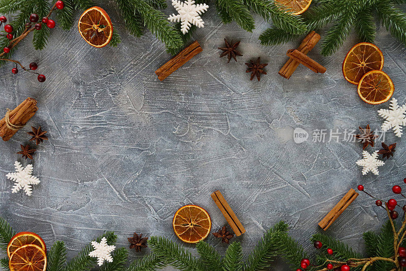 节日圣诞节的形象设计海报框架云杉针，红莓，肉桂棒，八角，干柑橘橙水果片和软糖冰霜雪花在灰色的背景，升高的视野，复制空间