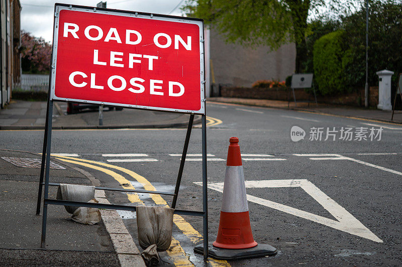 在一个城镇的一个路口有红色的道路封闭标志