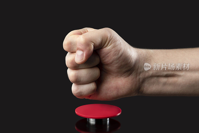 一个男人的手按下了一个红色的大按钮。黑色背景上的红色按钮。使用核武器或大规模杀伤性化学武器的威胁。一按按钮火箭就发射了