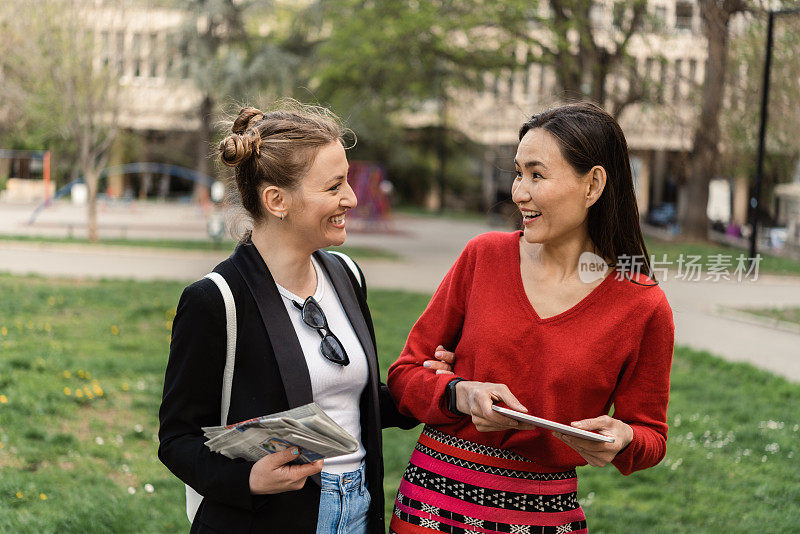 两个快乐的女人在移动中使用平板电脑的肖像