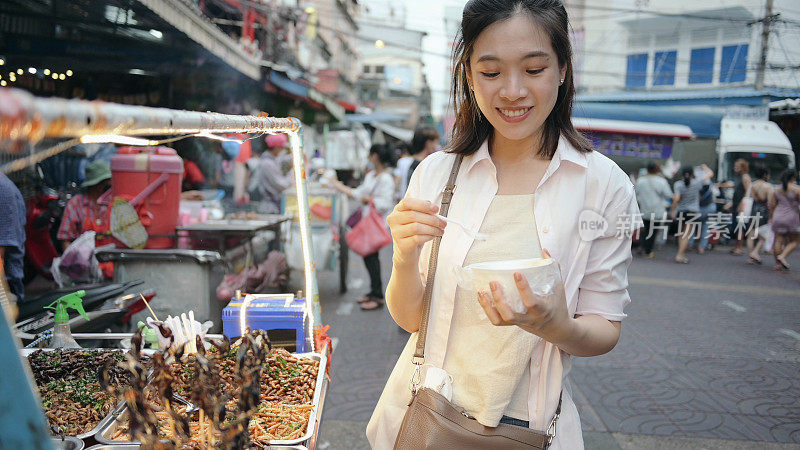 年轻的亚洲当地人吃异国街头食品油炸昆虫蝗虫蝎子毛毛虫在yaaowarat当地街头食品市场在泰国曼谷