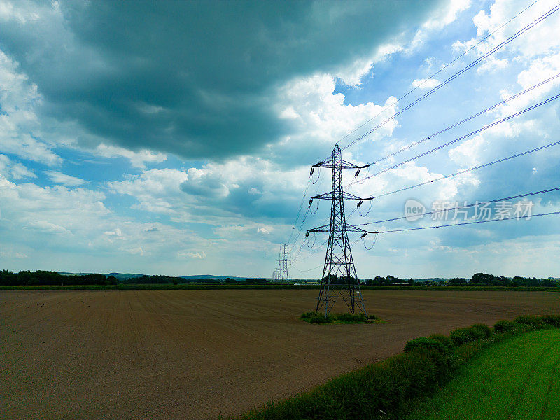 中景航拍图，输电塔承载着高压电缆横跨英国乡村
