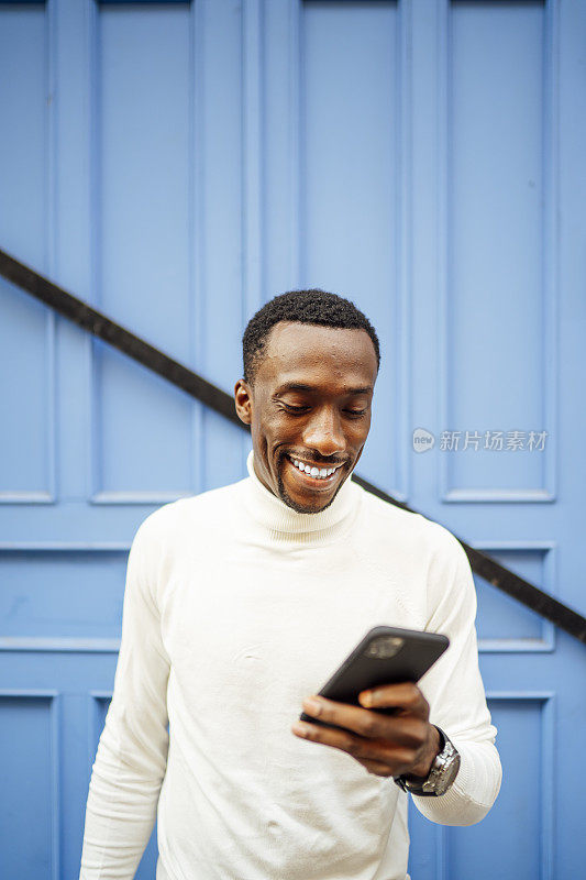 一个穿高领毛衣的黑人男子正在看他的手机