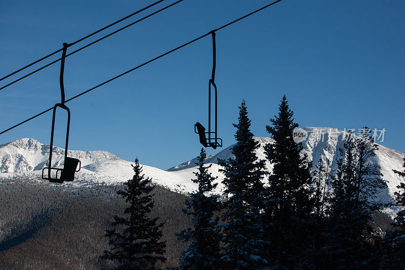 滑雪升降机椅轮廓与高山背景。