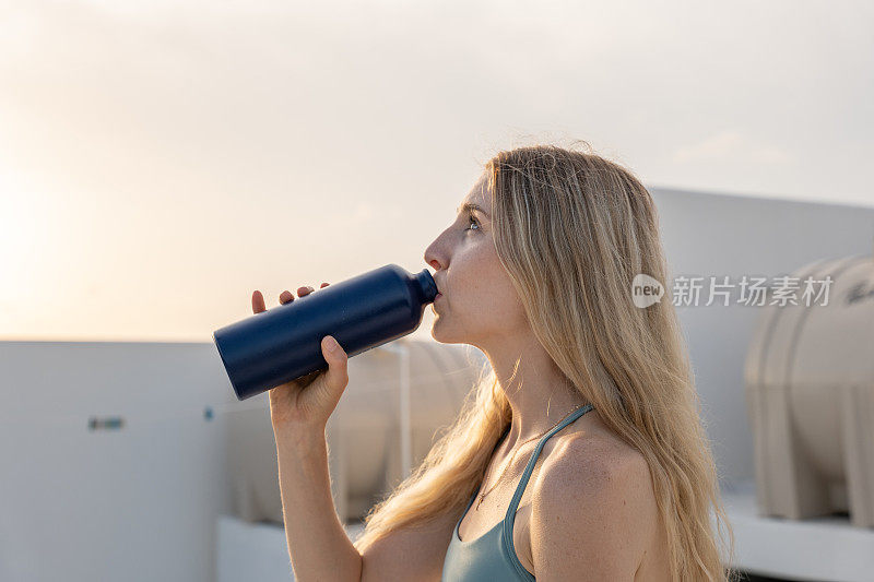 年轻女子用可重复使用的瓶子喝水的肖像