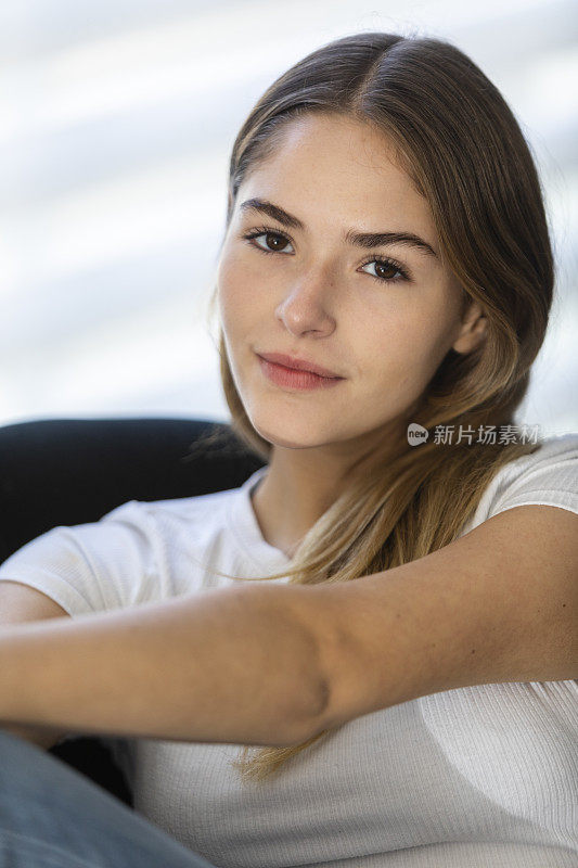 一个十几岁的女孩坐在房子里的椅子上