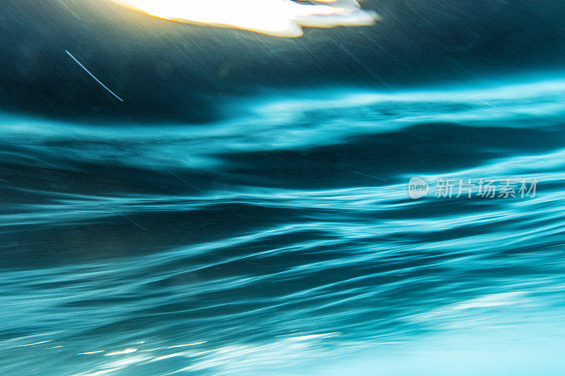 一种抽象的艺术场景，波浪在戏剧性的光线下在水下破碎