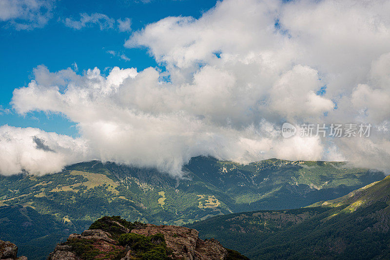 在一个阳光明媚的夏日里，有美丽的山峦和岩石景观。