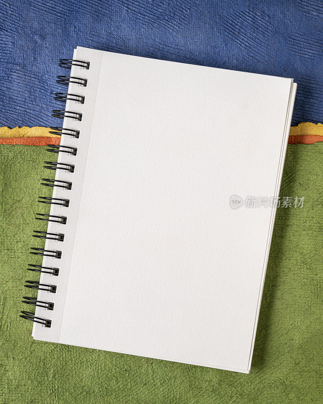 空白螺旋速写本与白色页对彩色抽象纸景观