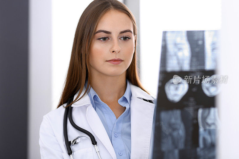 女医生在医院靠窗检查x光片。正在工作的外科医生或整形外科医生。医学和保健概念