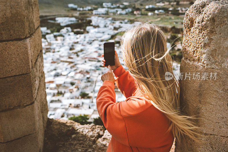 旅行博主用智能手机拍摄罗得岛林多斯镇的照片，一名希腊旅行者从雅典卫城观光鸟瞰图，夏季度假户外生活方式