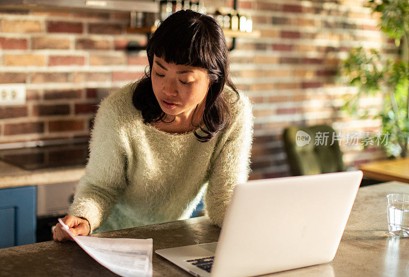 年轻的亚洲女性在家里的笔记本电脑上工作