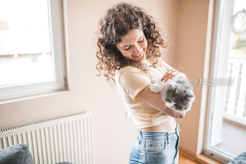 微笑的卷发女人手里抱着她可爱的猫