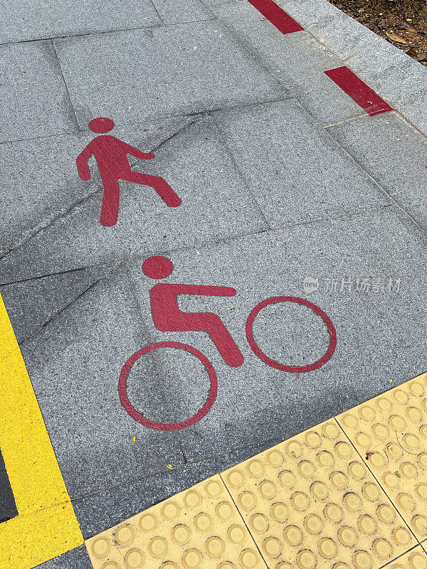铺路石上自行车和行人专用道标志的特写图像，红色自行车和行人标志，高架视图，重点放在前景