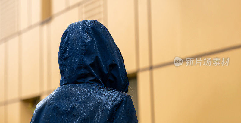 一个穿着蓝色雨衣的女人站在雨中。