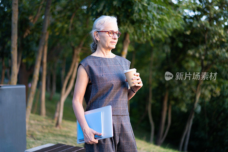 西班牙资深商务女士的肖像，灰白头发，复古眼镜，喝着咖啡。老太太拿着笔记本，蓝色笔记本和咖啡杯