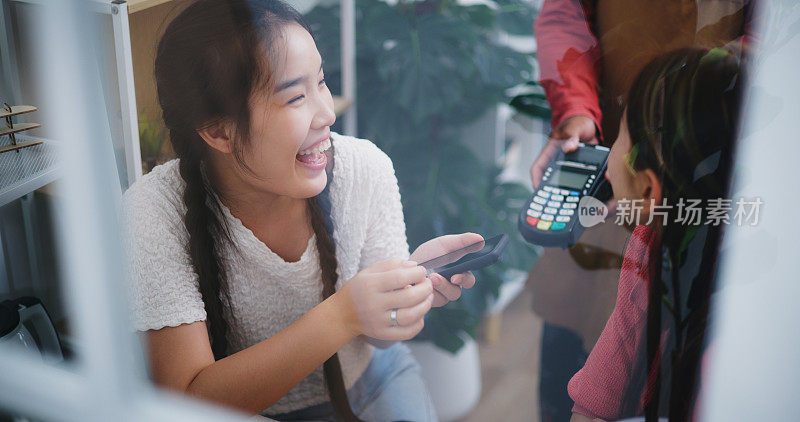 两名年轻女子在咖啡店用信用卡和智能手机付款