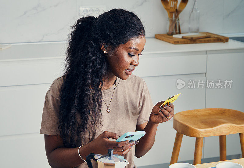 美丽快乐的女人在厨房里，用手机购物用数字支付