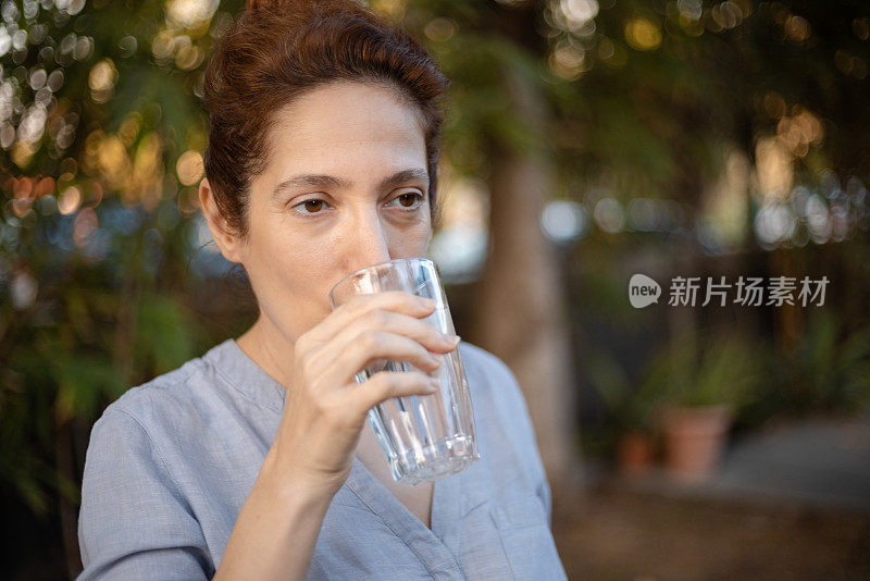 一名白人妇女正在喝一口冰水，这是治疗敏感牙齿系列的一部分