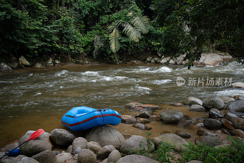 蓝色充气筏放置在河边，准备进行河上冒险。