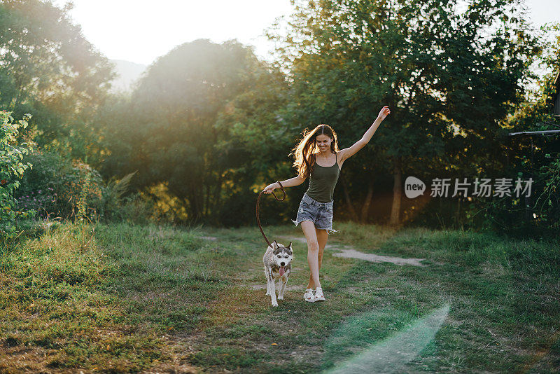 秋天黄昏时分，一位妇女牵着一只狗在森林里散步。与你心爱的狗一起进行生活方式运动训练