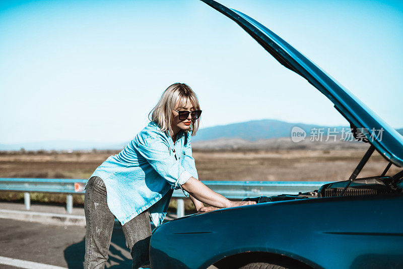 现代女性检查汽车发动机过热后，在道路上