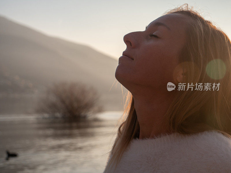 年轻女子闭眼沉思，仰望天空，满怀希望和信念