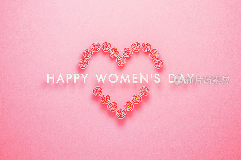 妇女节概念-在粉红色的背景上用粉红色的玫瑰做成的心里面写着妇女节快乐的信息