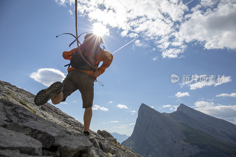 登山者在岩石山脊上跳跃，后面拖着绳子