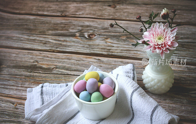 复活节和春天的装饰。巧克力杏仁蛋放在碗里，放在木桌上的抹布上