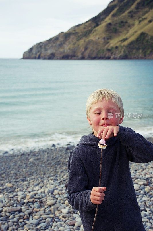 男孩在海边吃煮棉花糖