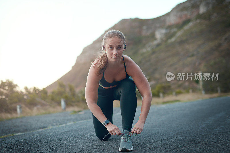 一个年轻女子在户外跑步前系鞋带的照片