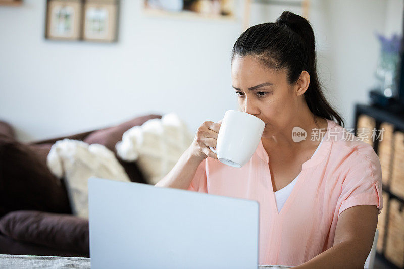 女人一边喝咖啡一边在家查收邮件