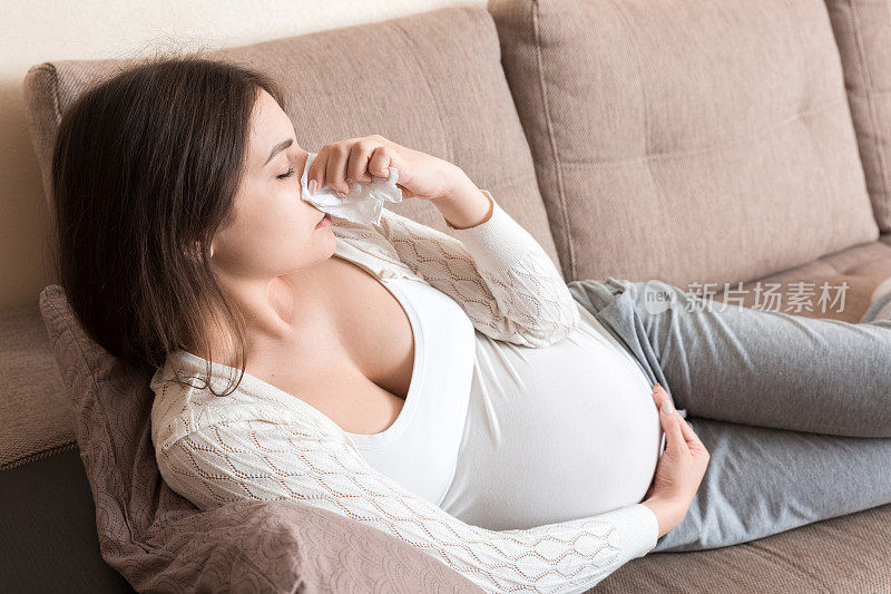 生病的孕妇在家里用纸巾擤鼻涕健康的千禧保健概念