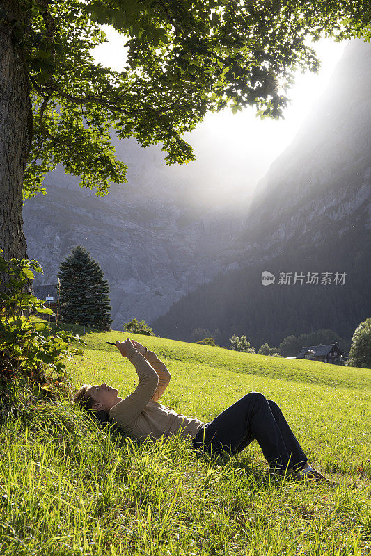 年轻人在绿草如茵的草地上，在茂密的树下休息