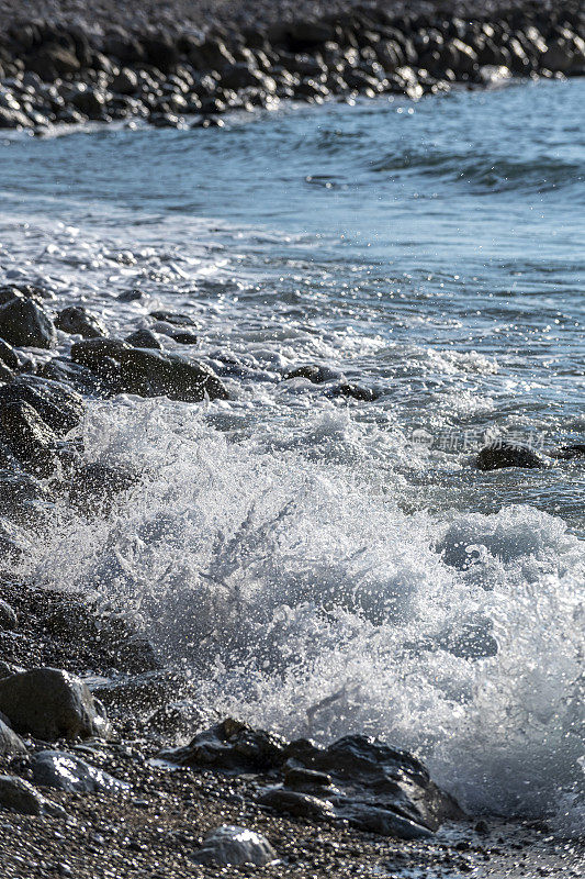 白色泡沫的波浪向海边的石头海岸靠近