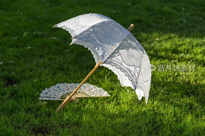 花园草地上的白色阳伞和手扇。马德里,西班牙