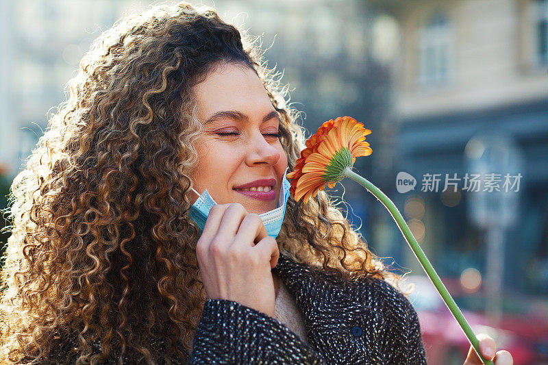 戴着面膜的年轻女子正在闻着花