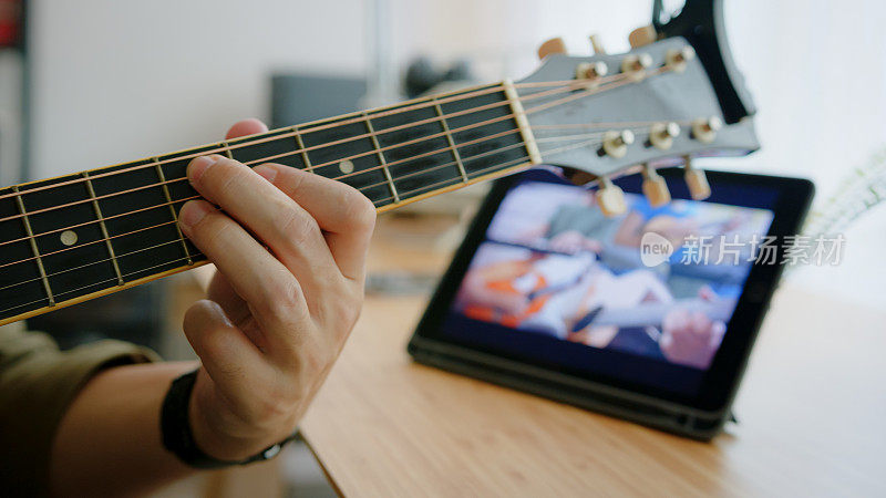 近距离的人的手演奏原声吉他与乐队通过视频会议音乐应用程序，而呆在家里。