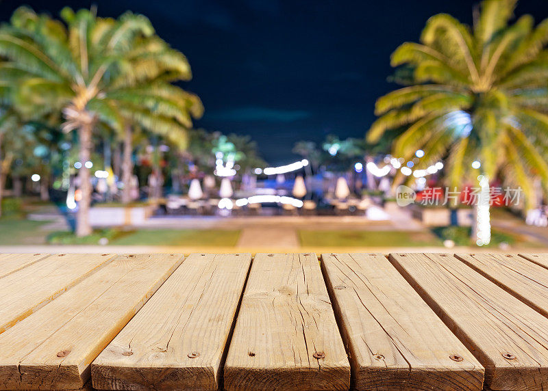 热带海滩度假胜地夜间模糊背景木制露台——热带度假夜生活概念