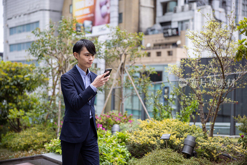 日本商人在城市中行走和使用智能手机