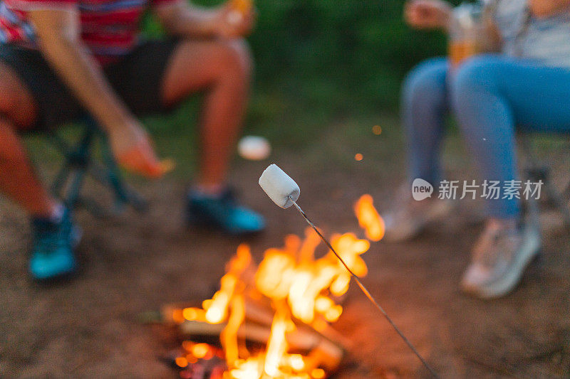 三个年轻朋友在篝火上烤棉花糖的特写