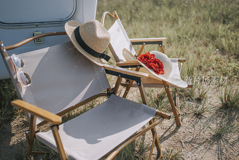 带草帽太阳镜的露营椅在稻田边的露营车旁