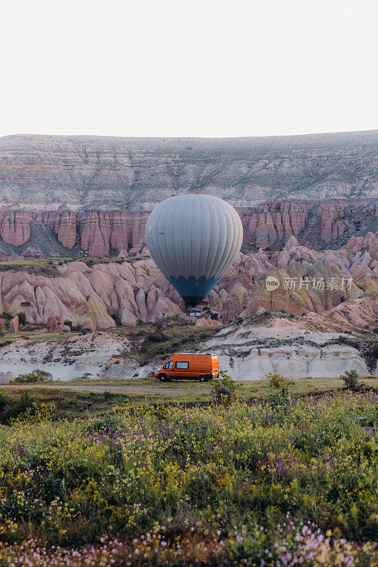 在卡帕多西亚，日出时热气球在露营车上的天空中飞行的风景