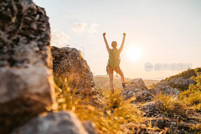 年轻的女徒步旅行者在登上山顶后欢呼