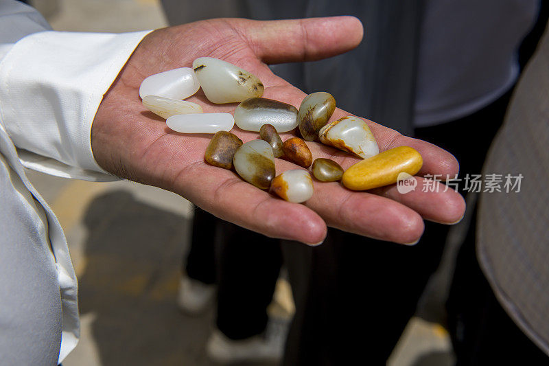 一个小贩在展示他从和田河河床上收集的玉石，中国新疆